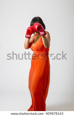 stock-photo-young-woman-wearing-a-low-cut-orange-dress-protecting-herself-with-red-boxing-glove-409878163.jpg
